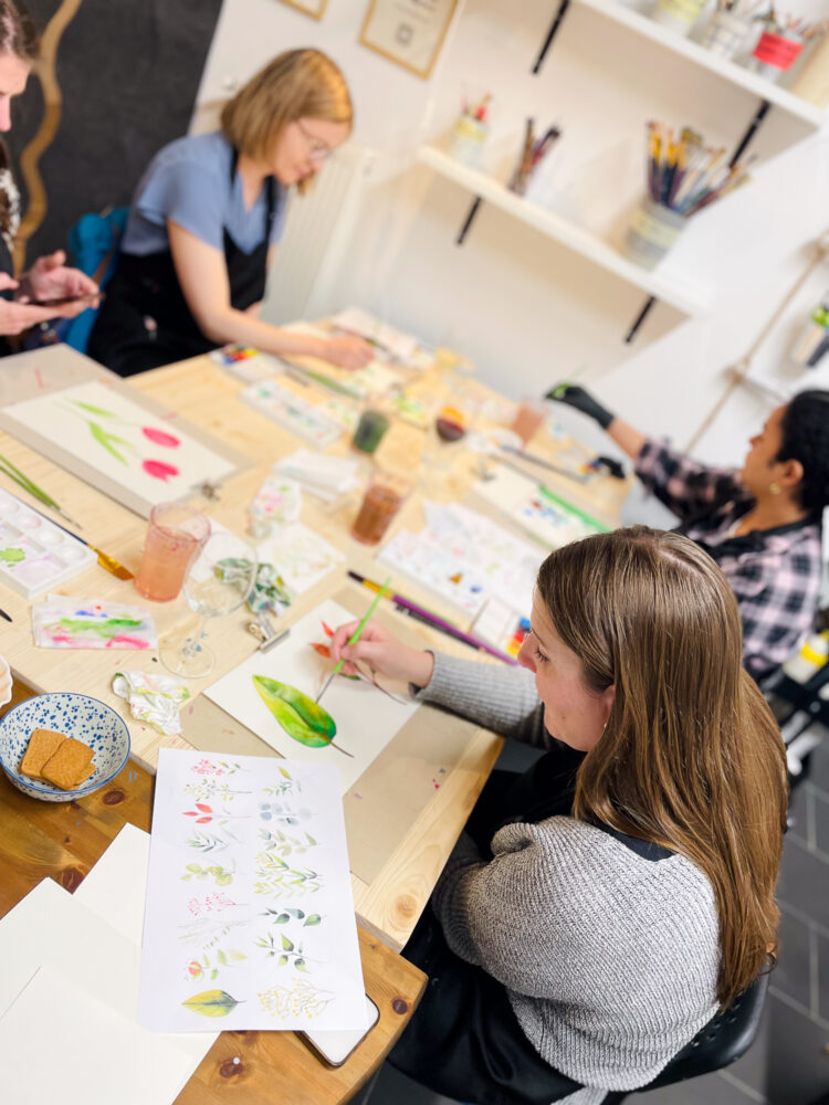 people painting watercolours around table art workshop